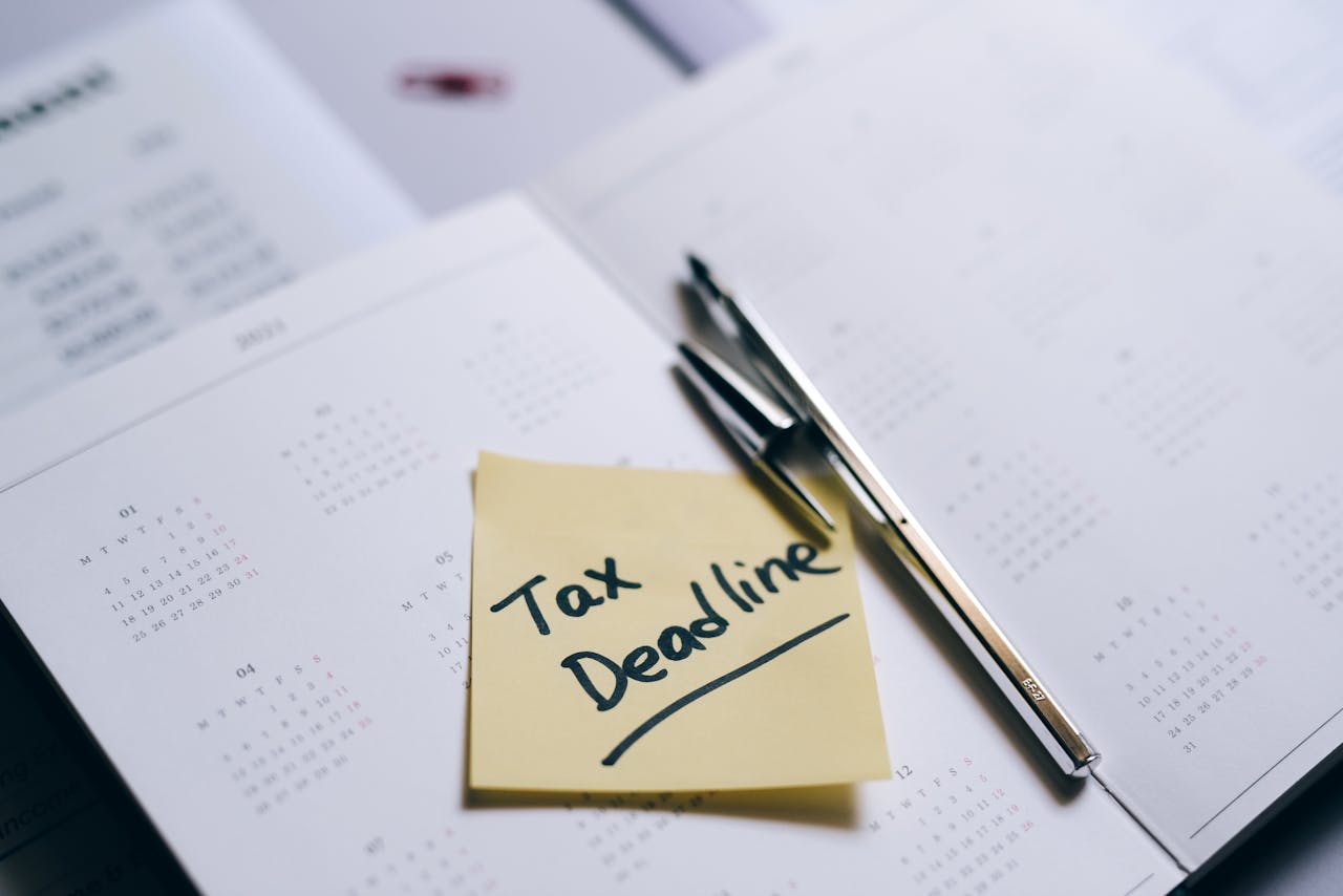 A close-up of a calendar with a sticky note reminding about the tax deadline.